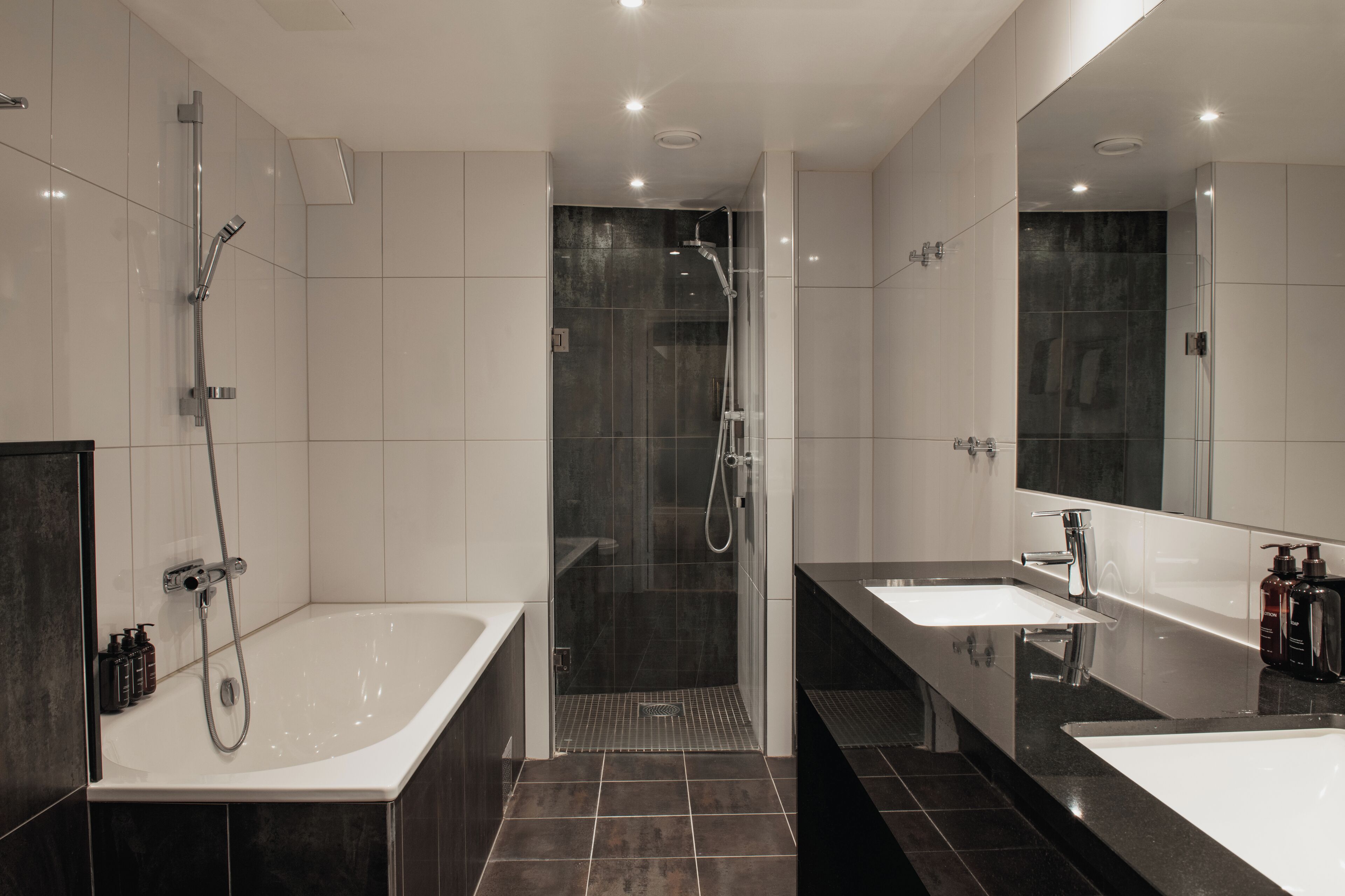 A modern bathroom with a large bathtub, a separate shower area, and two sinks.