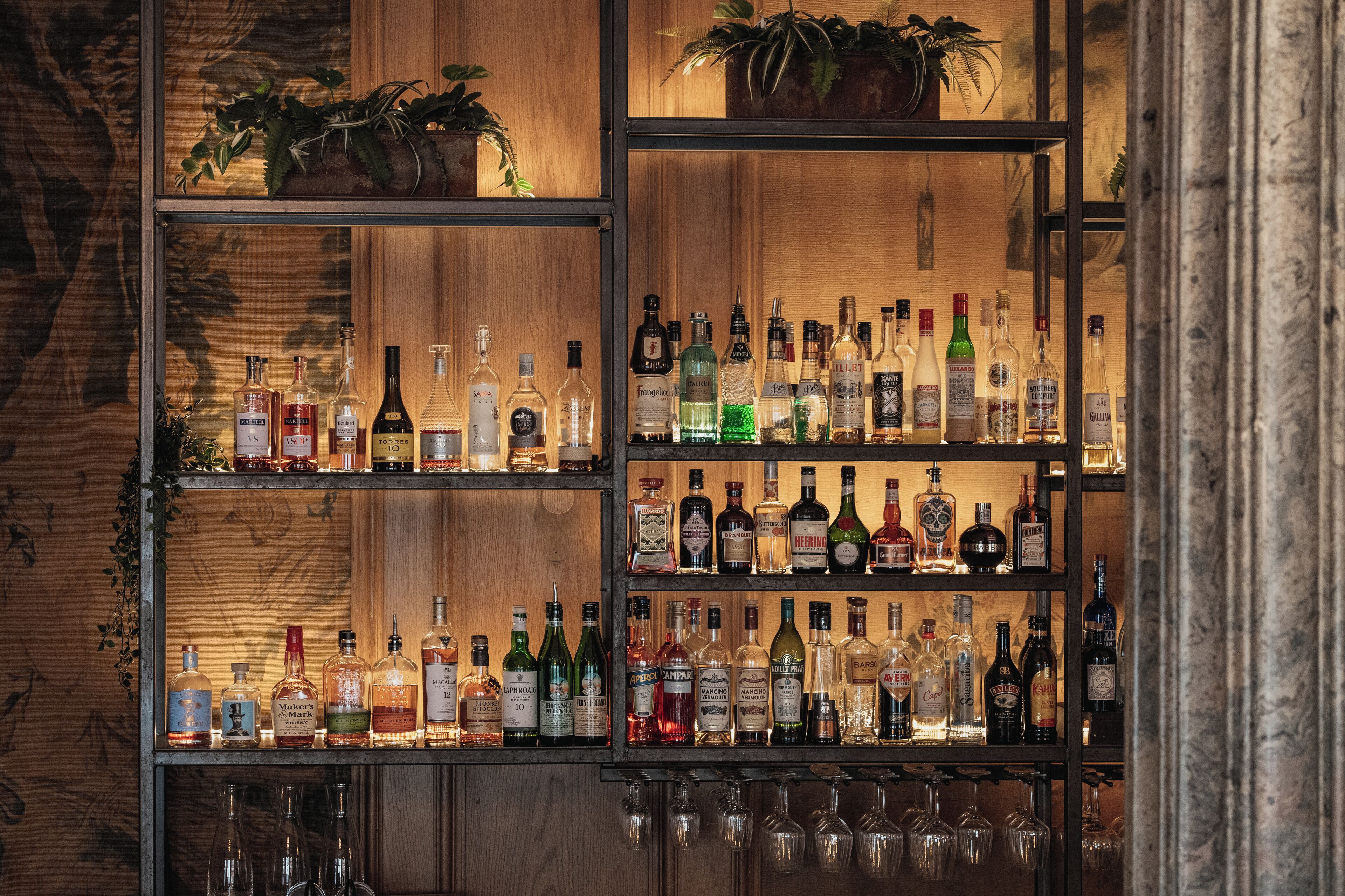 Um bar com várias prateleiras repletas de garrafas de bebidas e copos.