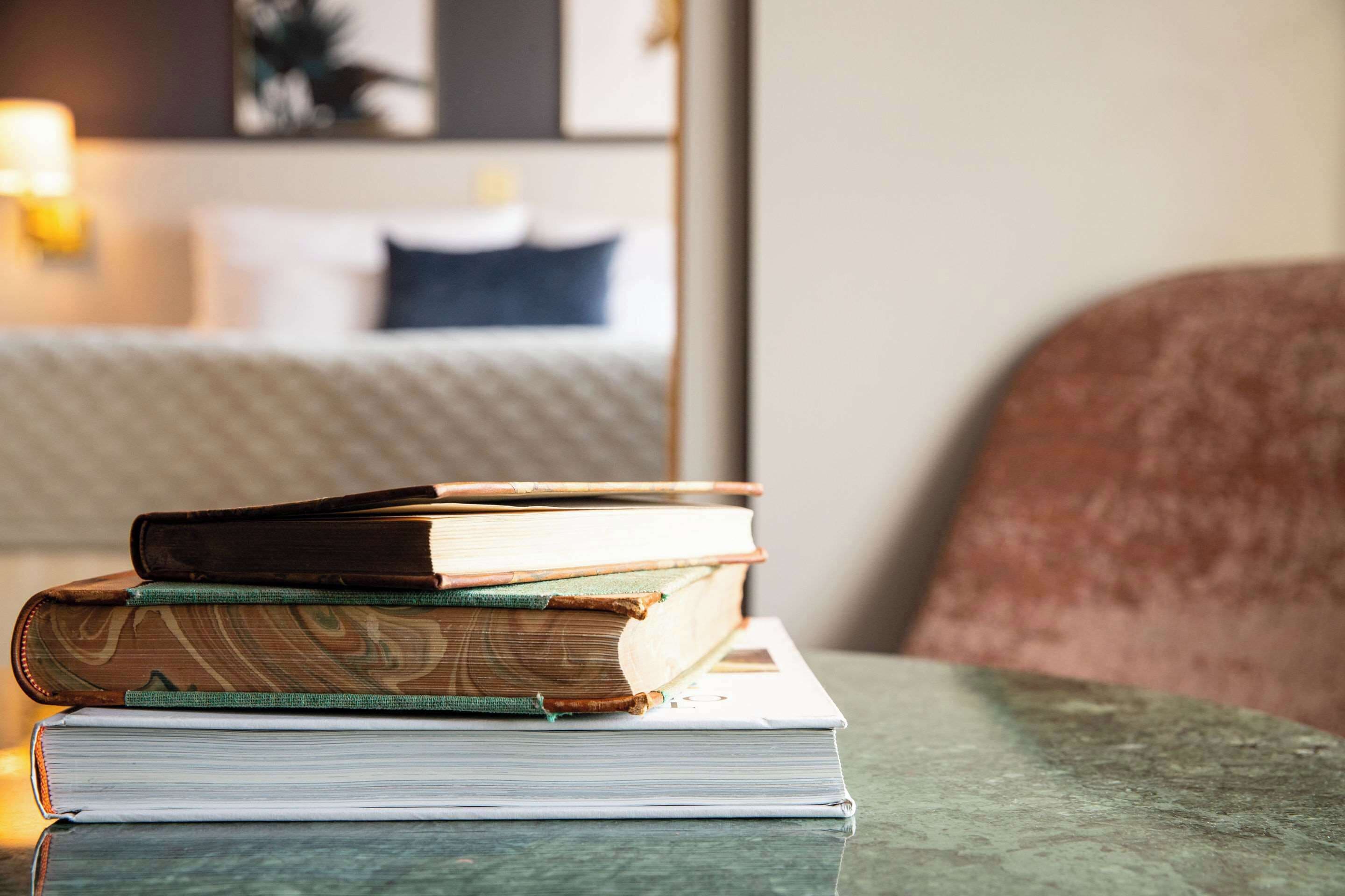 A stack of books on a table with a blurred background of a room.