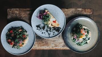 Three plates of food on a wooden board.