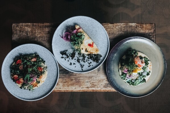 Three plates of food on a wooden board.