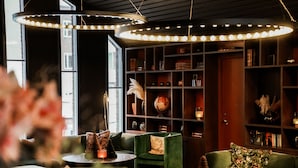 A cozy room with a green sofa, a small table with candles, and a bookshelf filled with books and decorative items.