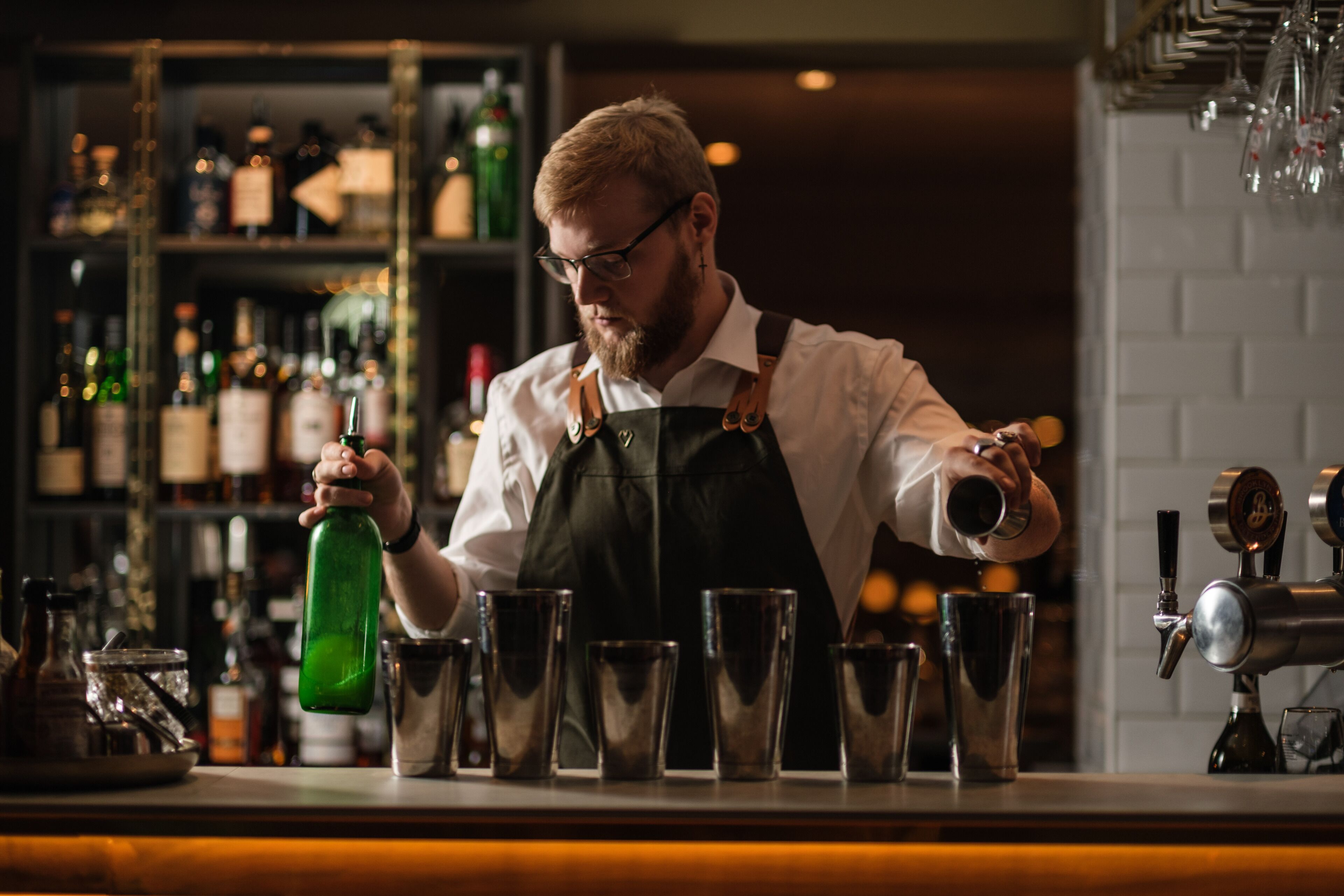 Un barman sirviendo una bebida en un vaso.
