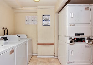 A laundry room with stacked washers and dryers, a notice sign, and a service sign. - Red Roof Inn Santa Ana (Santa Ana)