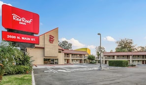 A Red Roof Inn with a large red sign, a parking lot, and a building with a red roof. - Red Roof Inn Santa Ana (Santa Ana)