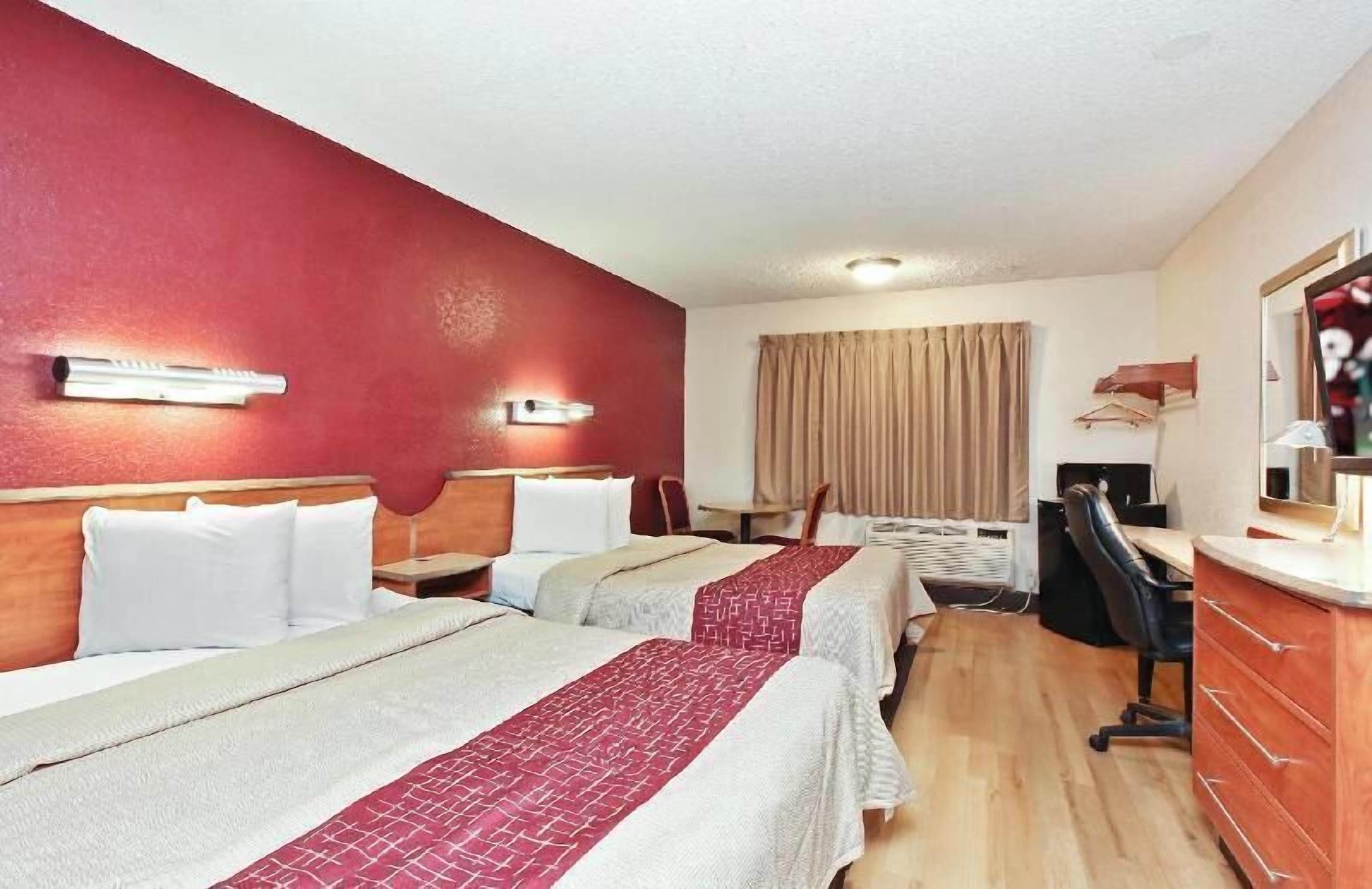 Habitació d'hotel amb dos llits, un escriptori, una cadira, un televisor i un armari.