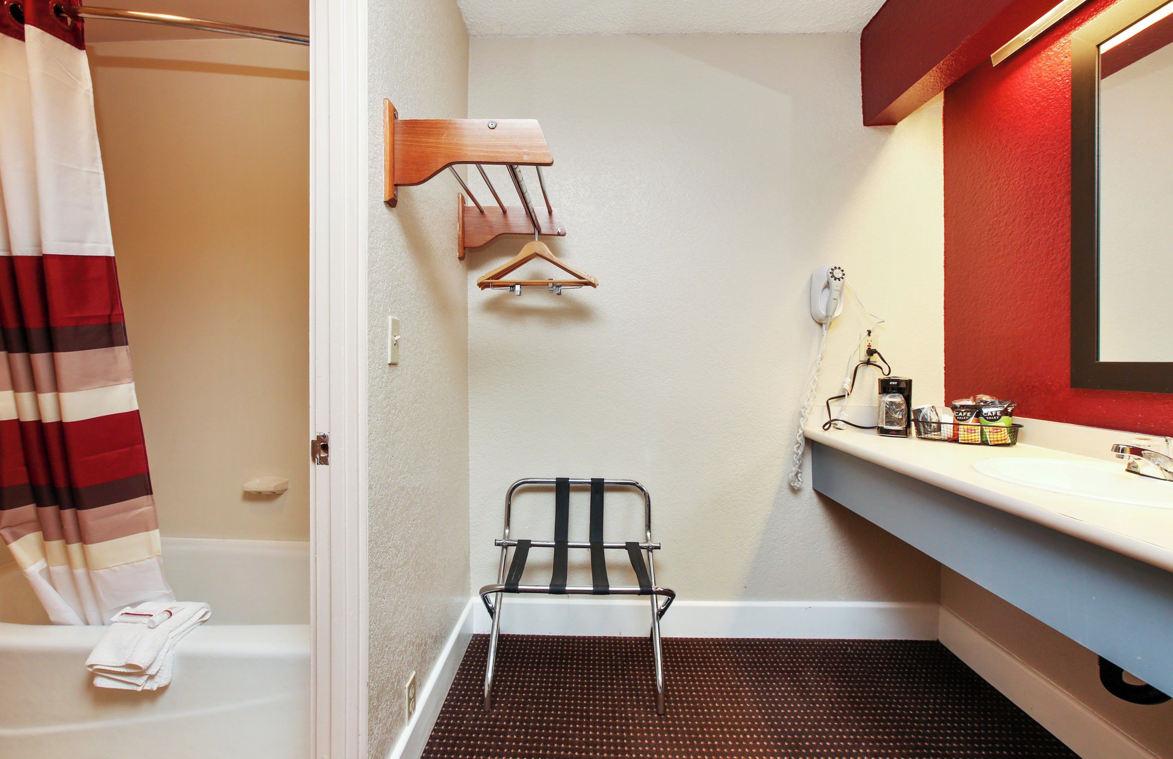 A bathroom with a shower, a towel rack, a sink with toiletries, and a mirror.