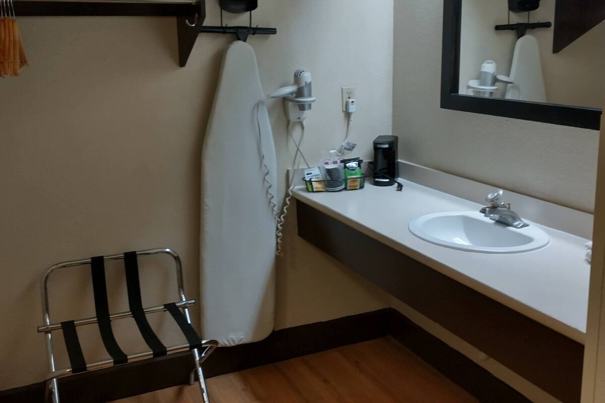 A bathroom with a wooden floor, a white sink, a mirror, and a towel rack.