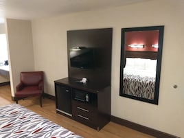 A hotel room with a bed, a TV on a cabinet, a chair, and a mirror.