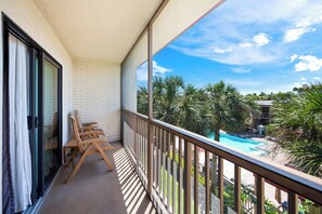 A balcony with a view of a swimming pool, palm trees, and a brick wall. - Red Roof Inn PLUS+ & Suites Naples Downtown-5th Ave S (Naples)