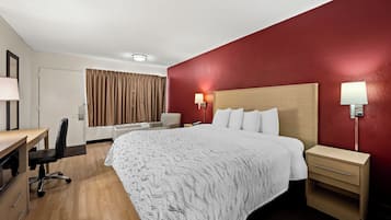 A hotel room with a bed, bedside tables, a desk, and a chair.