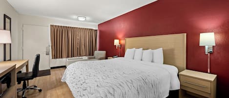 Una habitación de hotel con una cama, mesitas de noche, un escritorio y una silla.