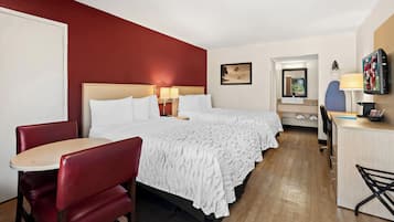 Una habitación de hotel con cama, escritorio, silla y televisor.