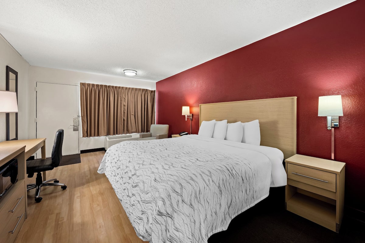 Een hotelkamer met een bed, nachtkastjes, een bureau en een stoel.