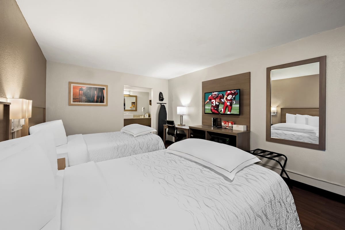 Een hotelkamer met twee bedden, een televisie, een bureau en een spiegel.
