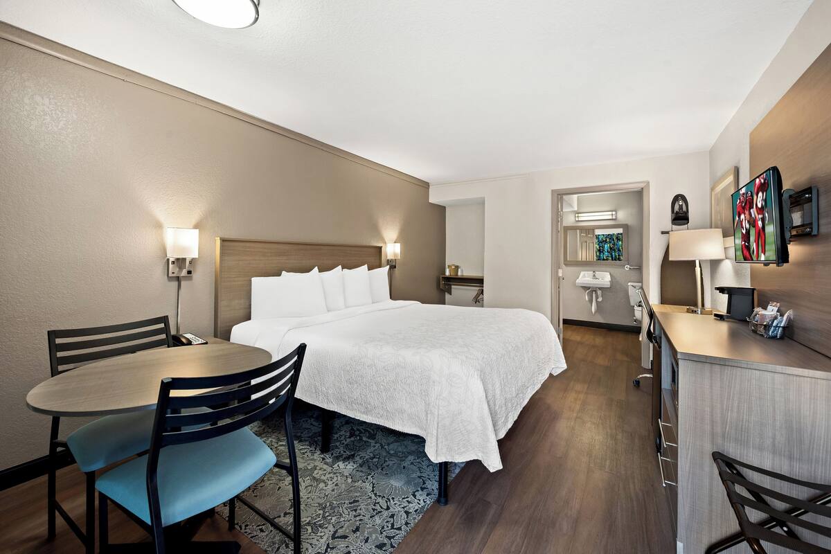Een hotelkamer met een bed, nachtkastjes, een bureau, een stoel en een kleine badkamer.