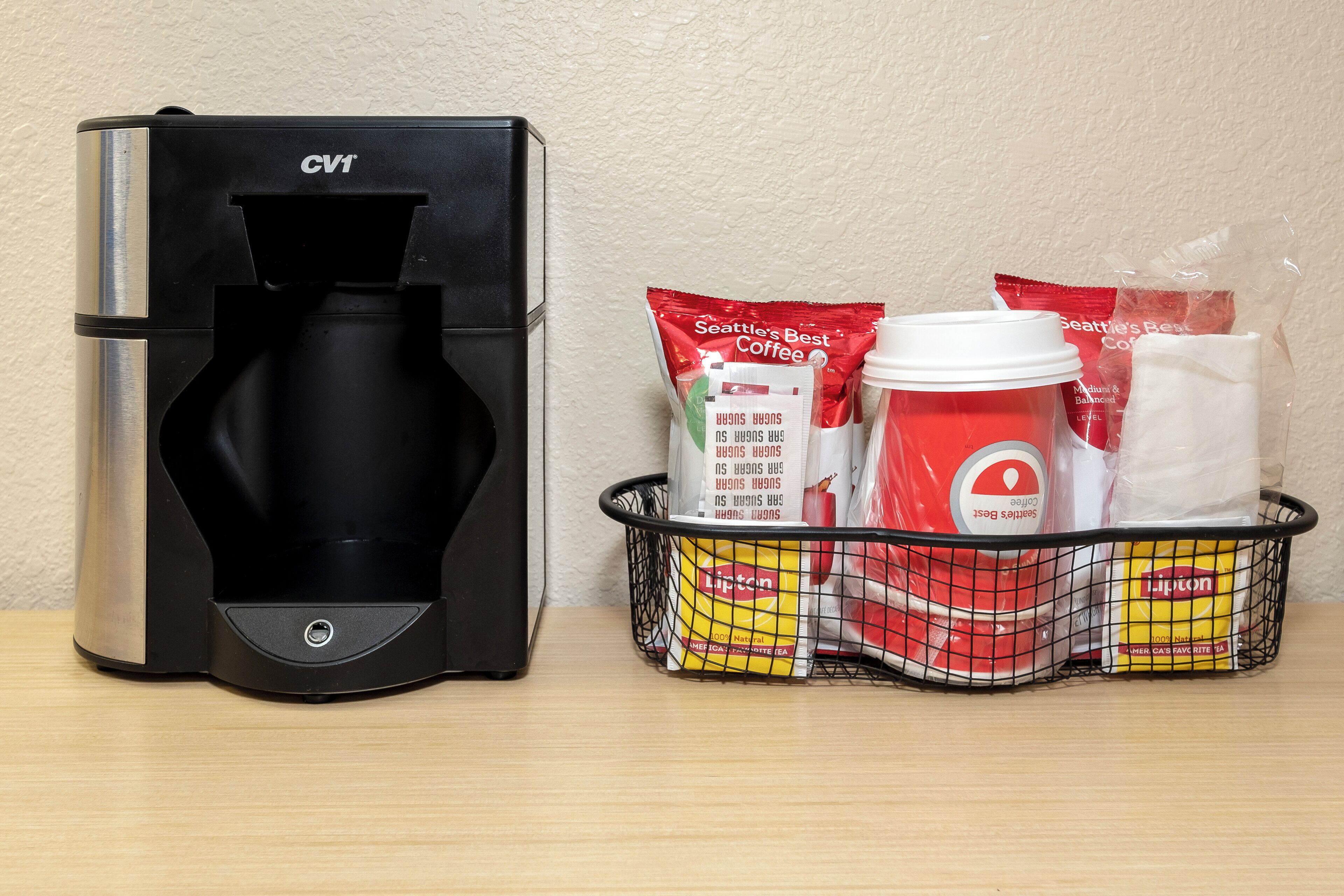 A coffee maker and a basket with coffee pods and a disposable cup.