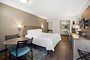 A hotel room with a bed, bedside tables, a desk, a chair, and a small bathroom. - Red Roof Inn PLUS+ & Suites Naples Downtown-5th Ave S (Naples)