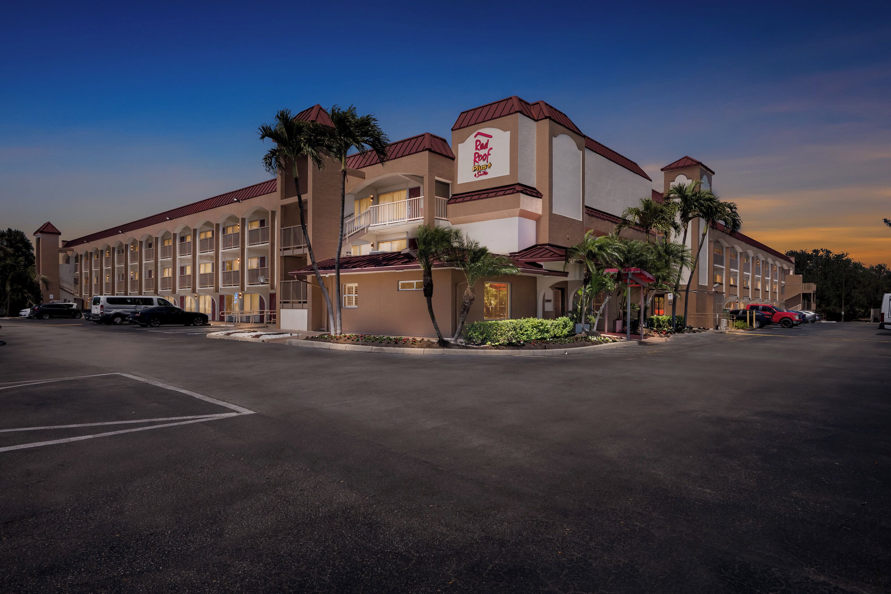 A hotel with a central courtyard, multiple balconies, and palm trees.