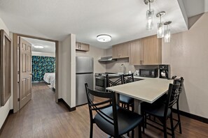 A modern kitchen with wooden cabinets, a dining table, and black chairs. - Red Roof Inn PLUS+ & Suites Naples Downtown-5th Ave S (Naples)