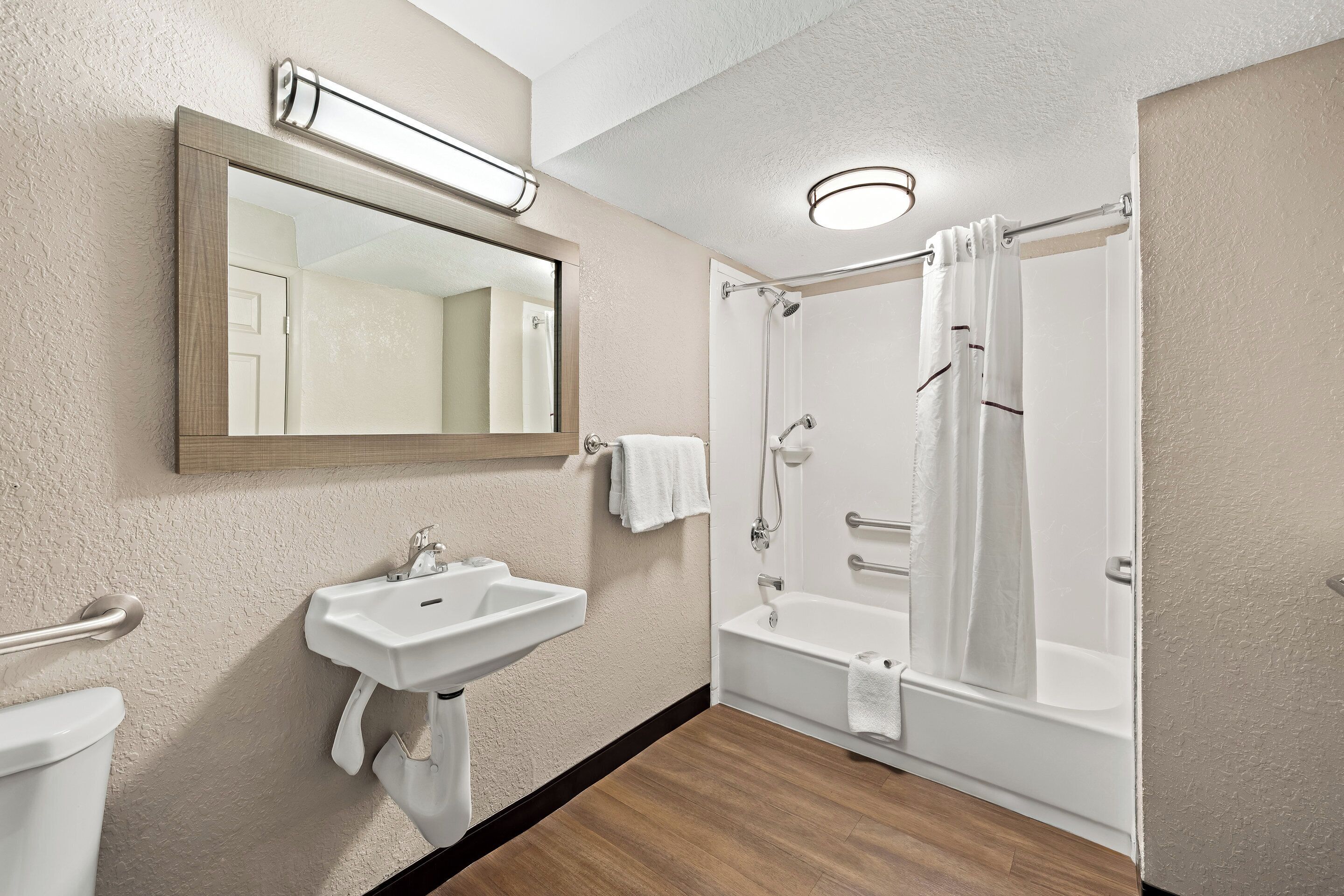 A bathroom with a sink, mirror, and shower.