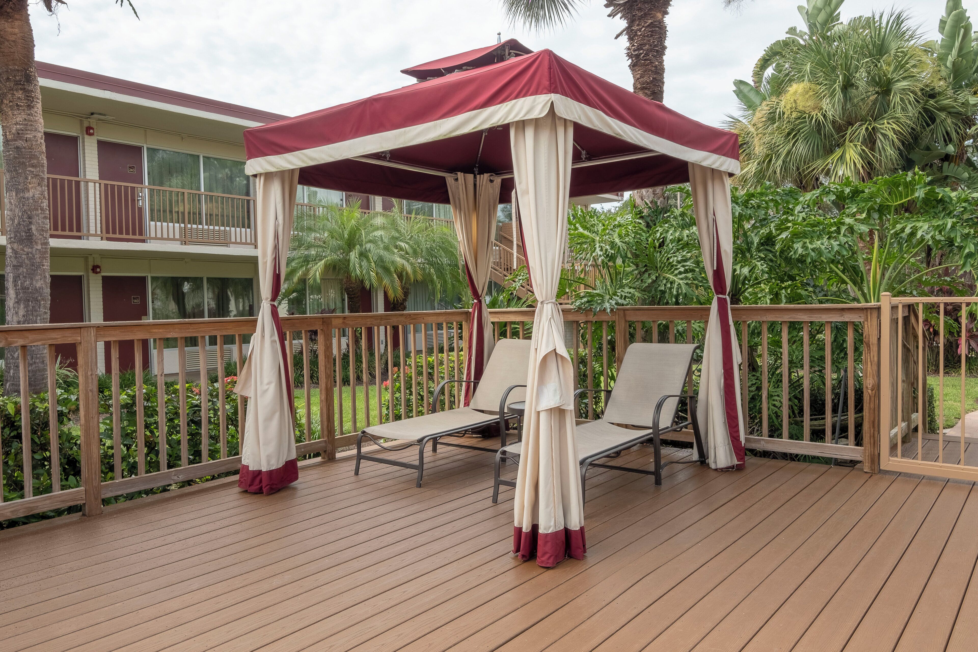 Una terraza de madera con toldo y dos sillones de relax.
