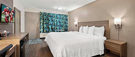 A hotel room with a bed, bedside tables, a desk, and a television.