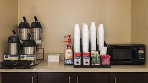 A coffee station with coffee makers, disposable cups, and a microwave. - Red Roof Inn PLUS+ Boston - Woburn/ Burlington (Woburn)