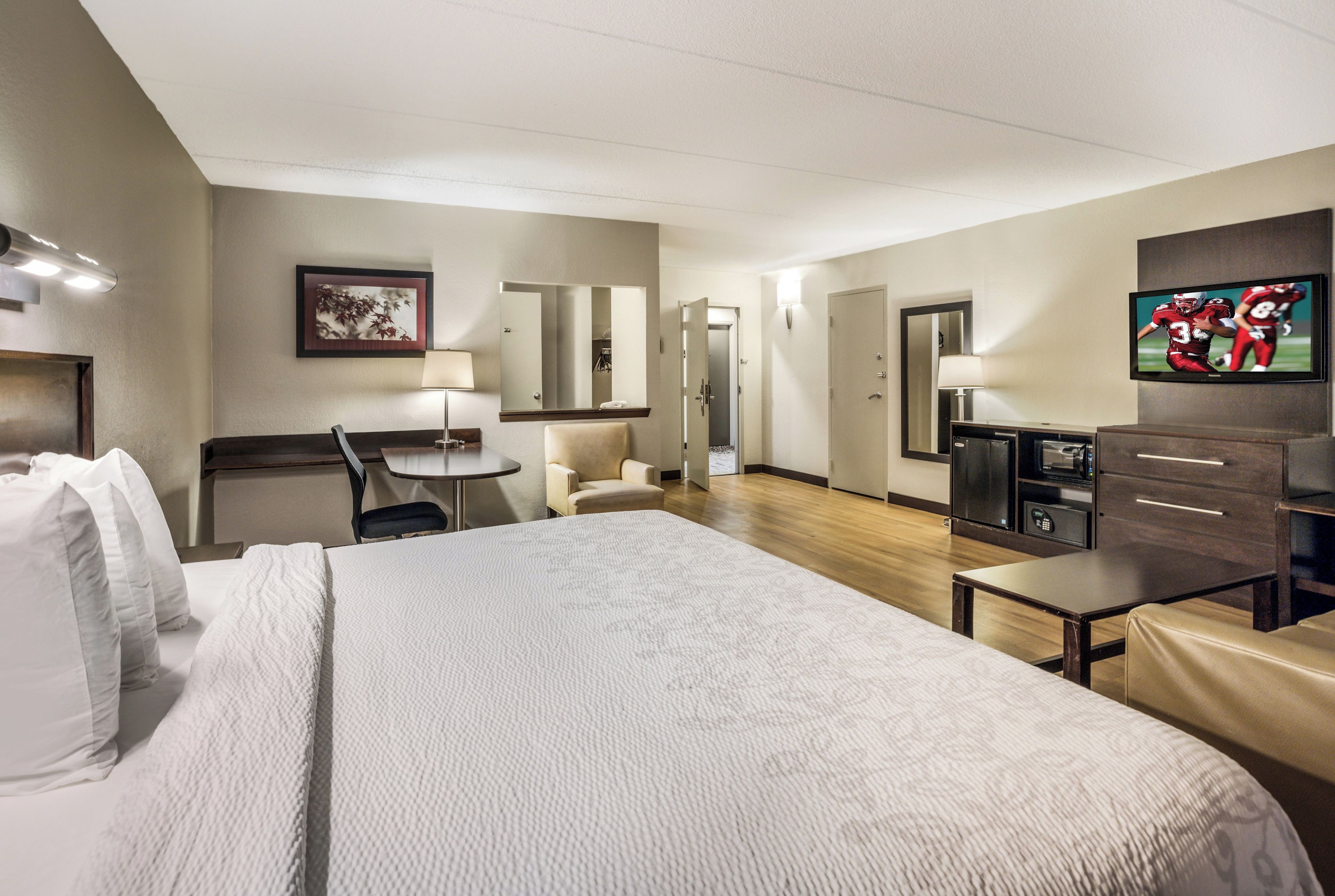 Una habitación de hotel con una cama grande, un escritorio, una silla, un televisor y un armario.