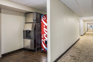 Corredor com máquina de vendas automática e refrigerador de Coca-Cola.