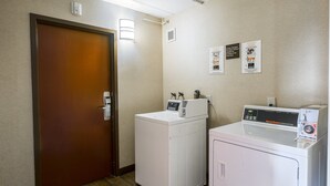 Un cuarto de lavandería con dos lavadoras, una puerta y una lámpara fijada a la pared.