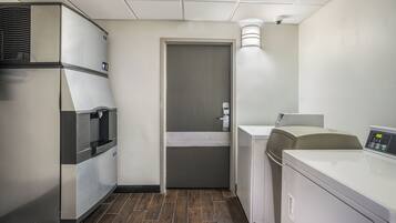A compact kitchen with a refrigerator, a coffee machine, and a washing machine.