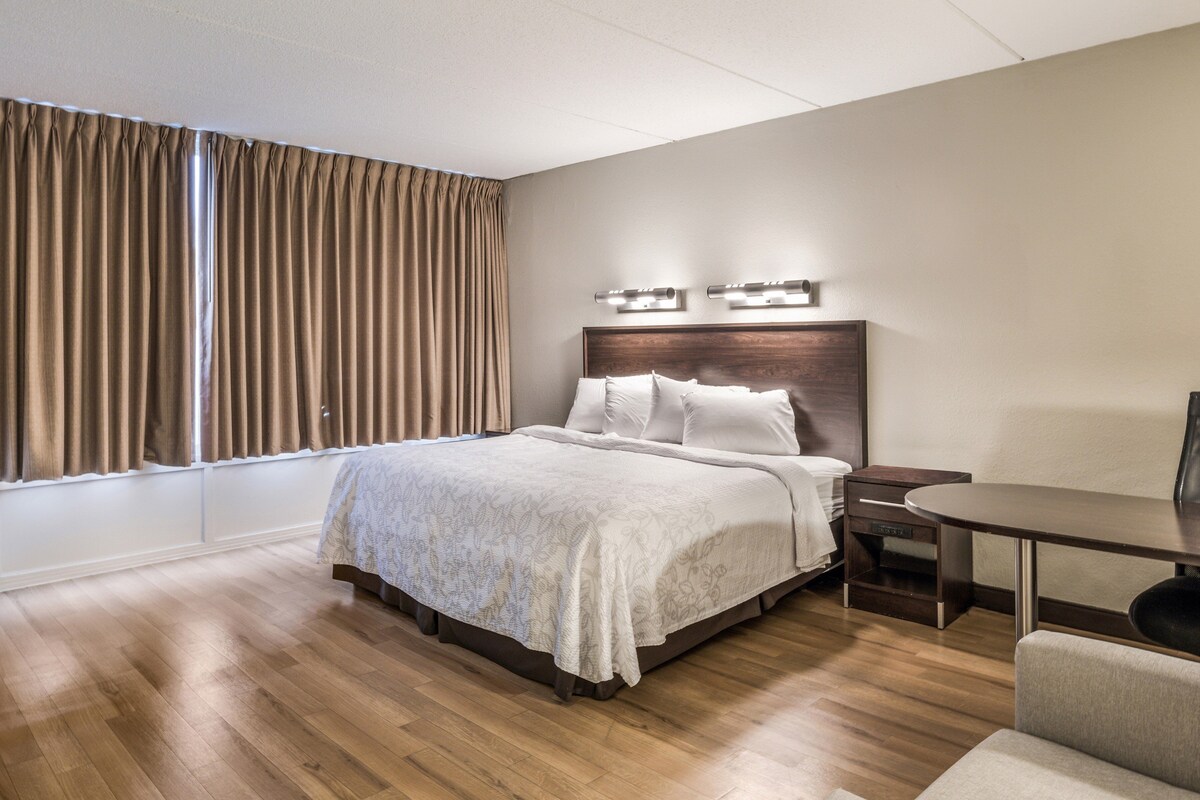 A hotel room with a bed, bedside table, and a desk with a chair.