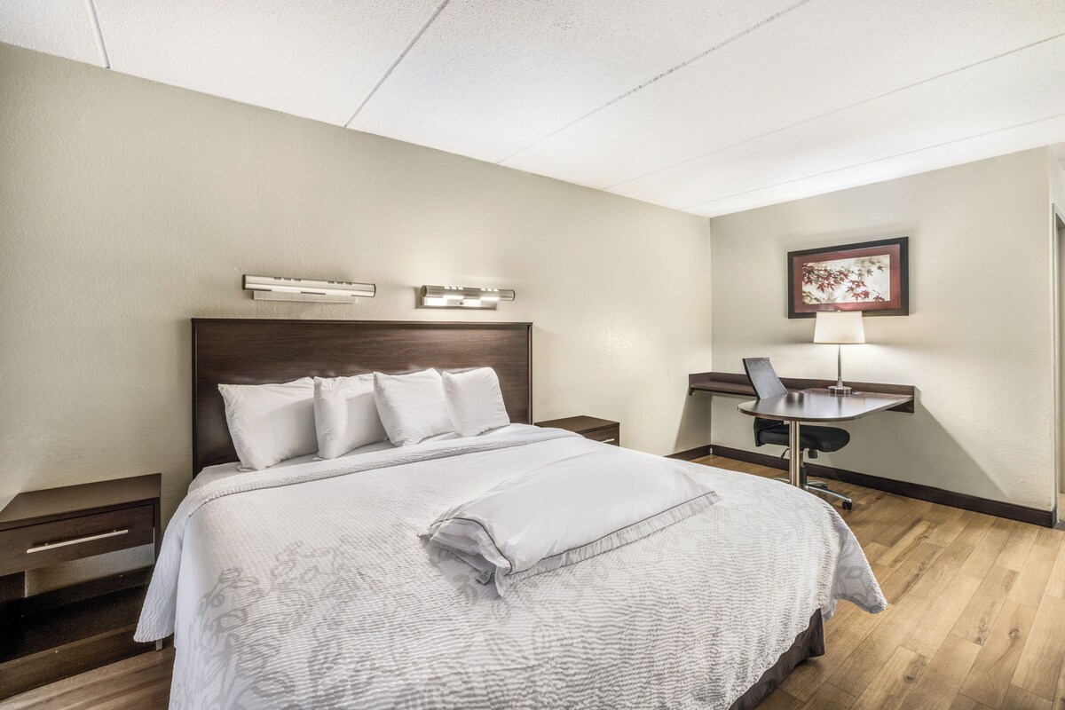 A hotel room with a large bed, a desk, and a chair.