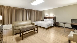 Una habitación de hotel con cama, sofá, escritorio, silla y televisor.