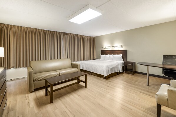 A hotel room with a bed, a sofa, a desk, a chair, and a TV. - Red Roof Inn PLUS+ Boston - Woburn/ Burlington (Woburn)