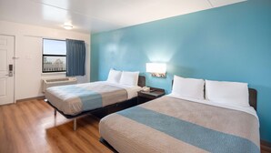 Een hotelkamer met twee bedden, een raam met gordijnen, een nachtkastje met een lamp en een deur.