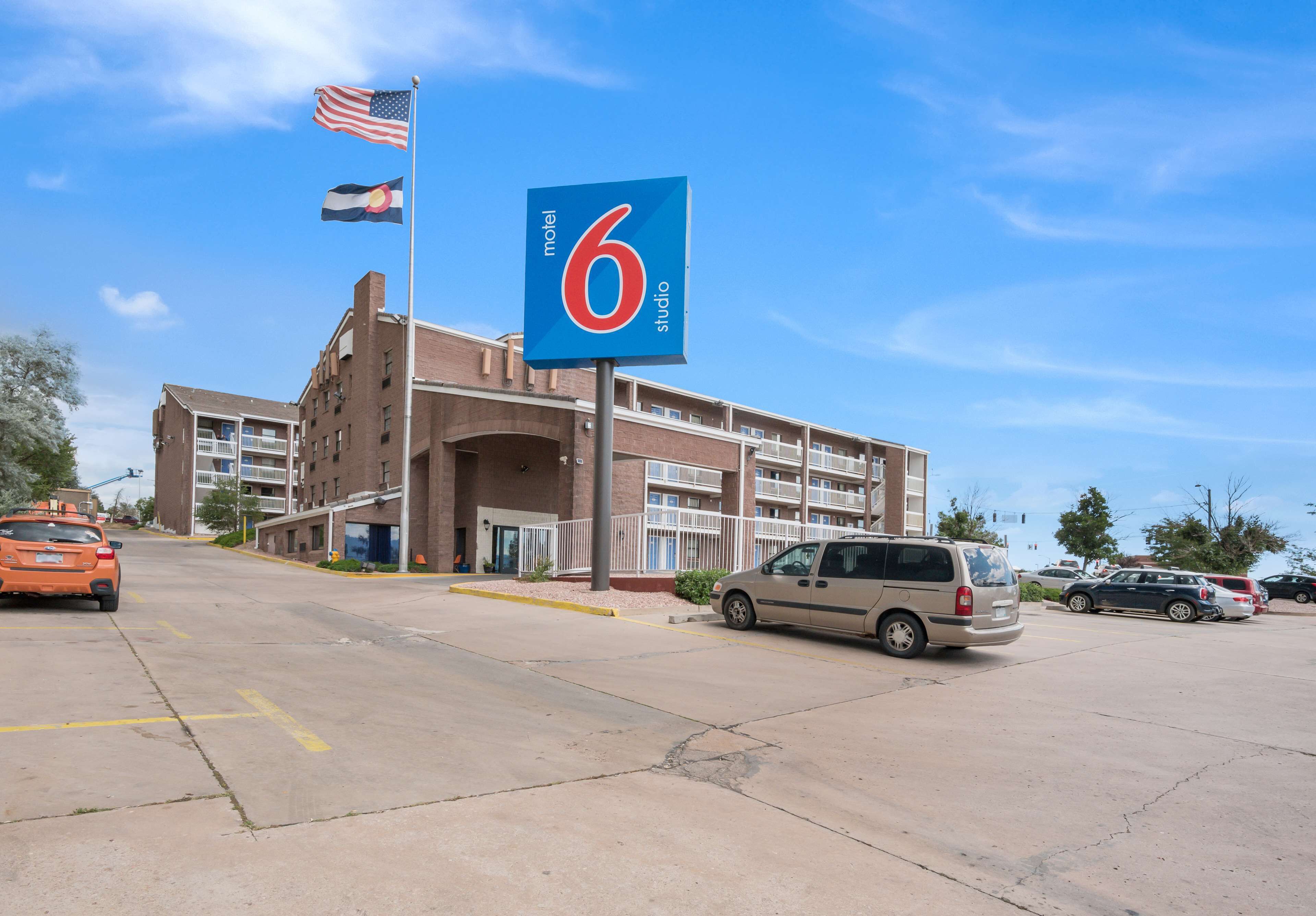 A motel with a prominent sign, a parking lot, and a flag.