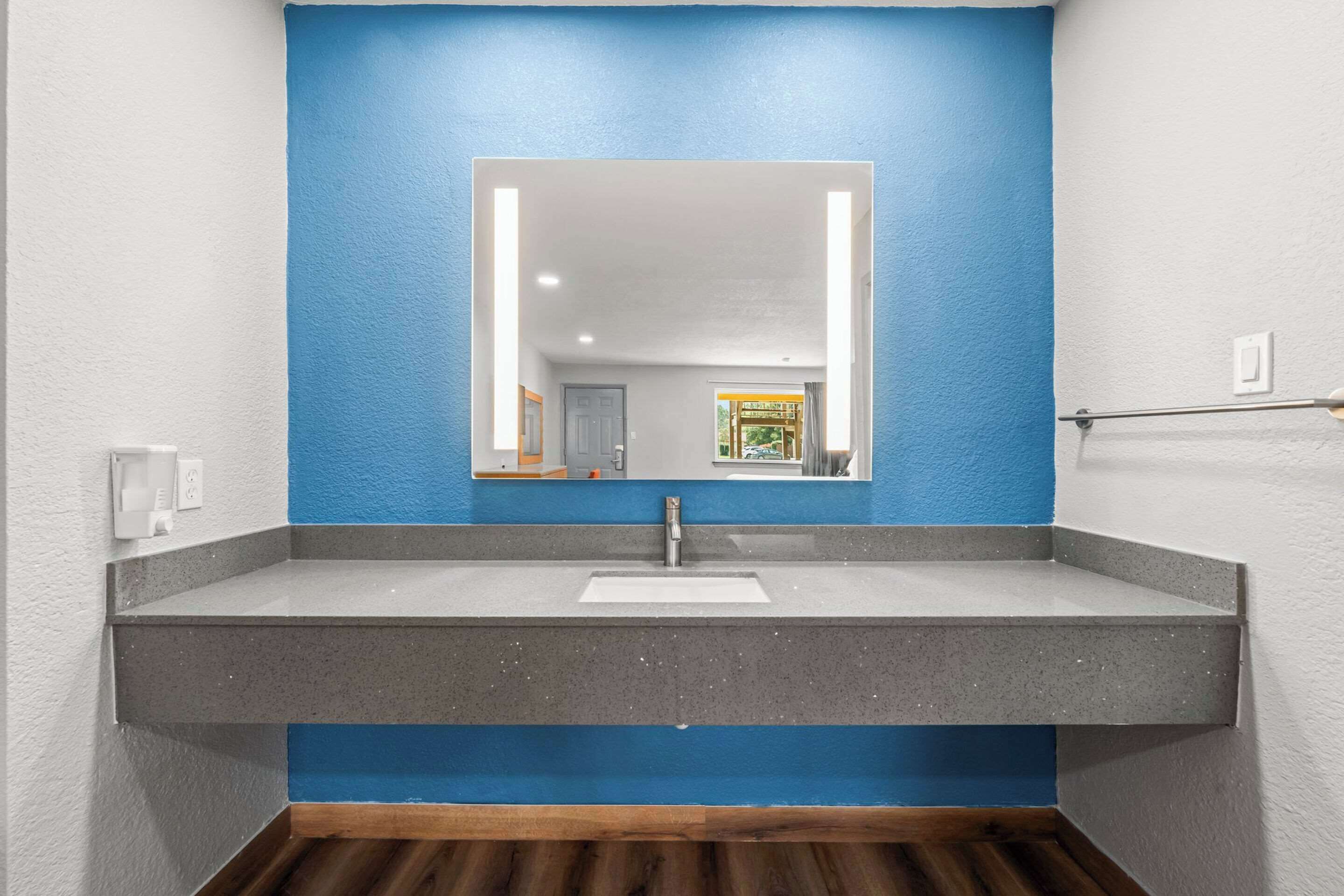 Un baño con una pared azul decorativa, un lavabo blanco y un espejo.