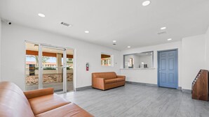 A spacious lobby with a leather sofa, a blue door, and a fire extinguisher. - Econo Lodge Inn & Suites Sealy (Sealy)