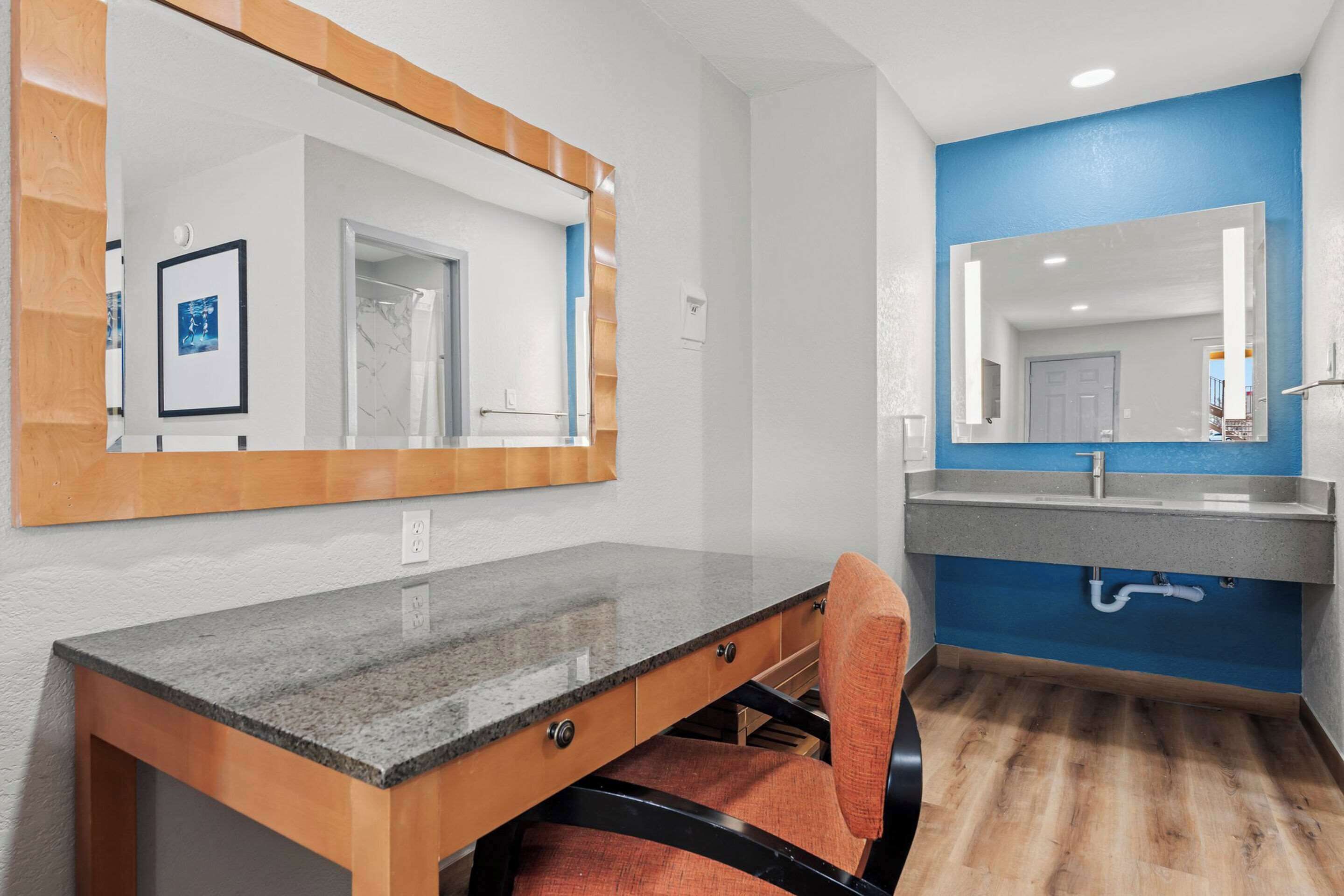 Un baño con tocador de madera, un espejo y una pared azul decorativa.