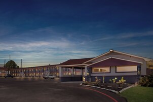 Un motel con un edificio central y una hilera de habitaciones contiguas.