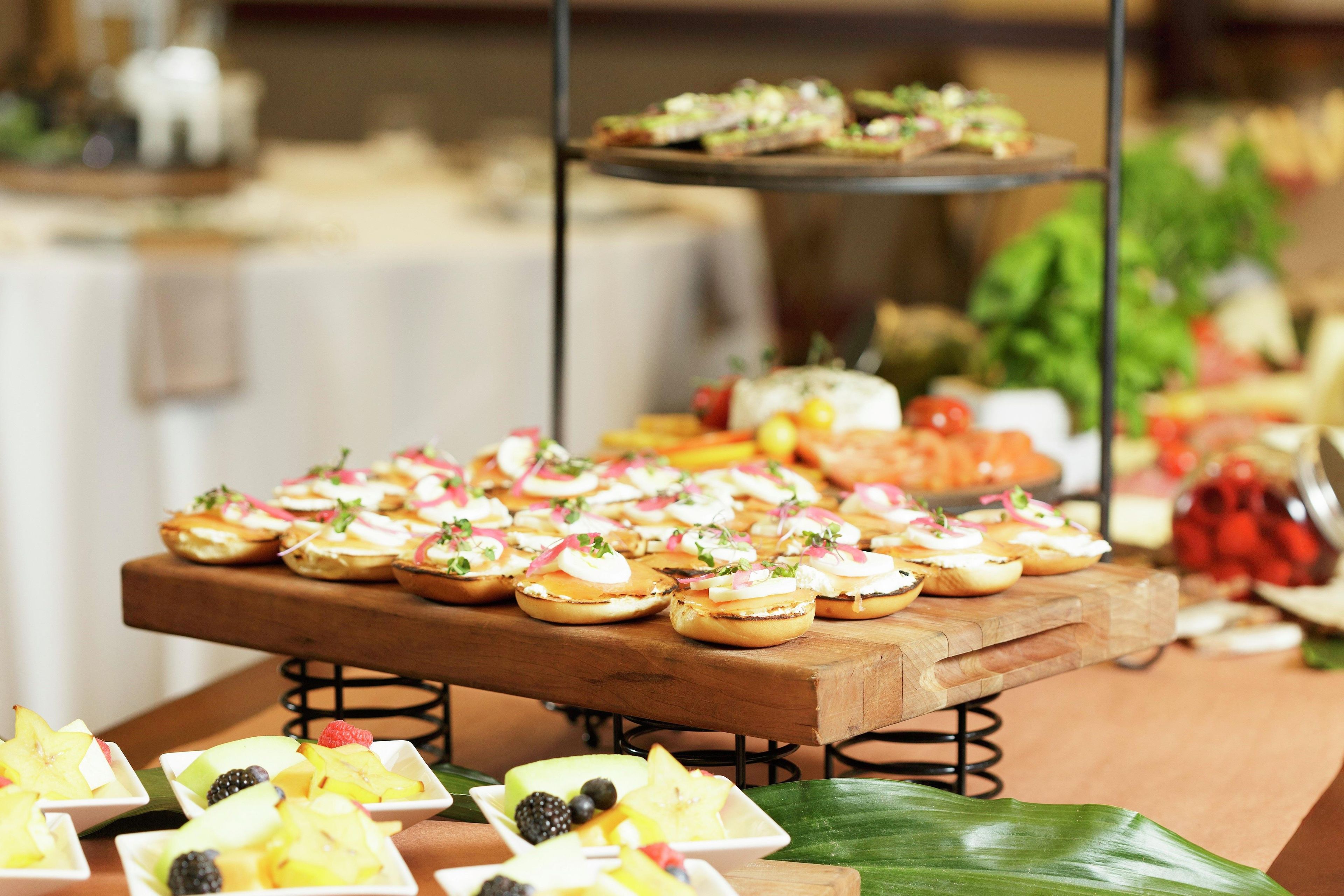 A buffet table with various food items, including fruit and sandwiches.