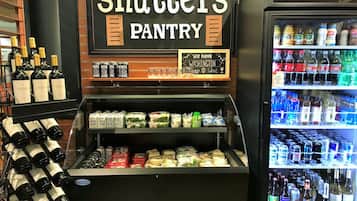 A display case with wine bottles and food items, a sign reading 'shutters pantry', and a refrigerator stocked with beverages.