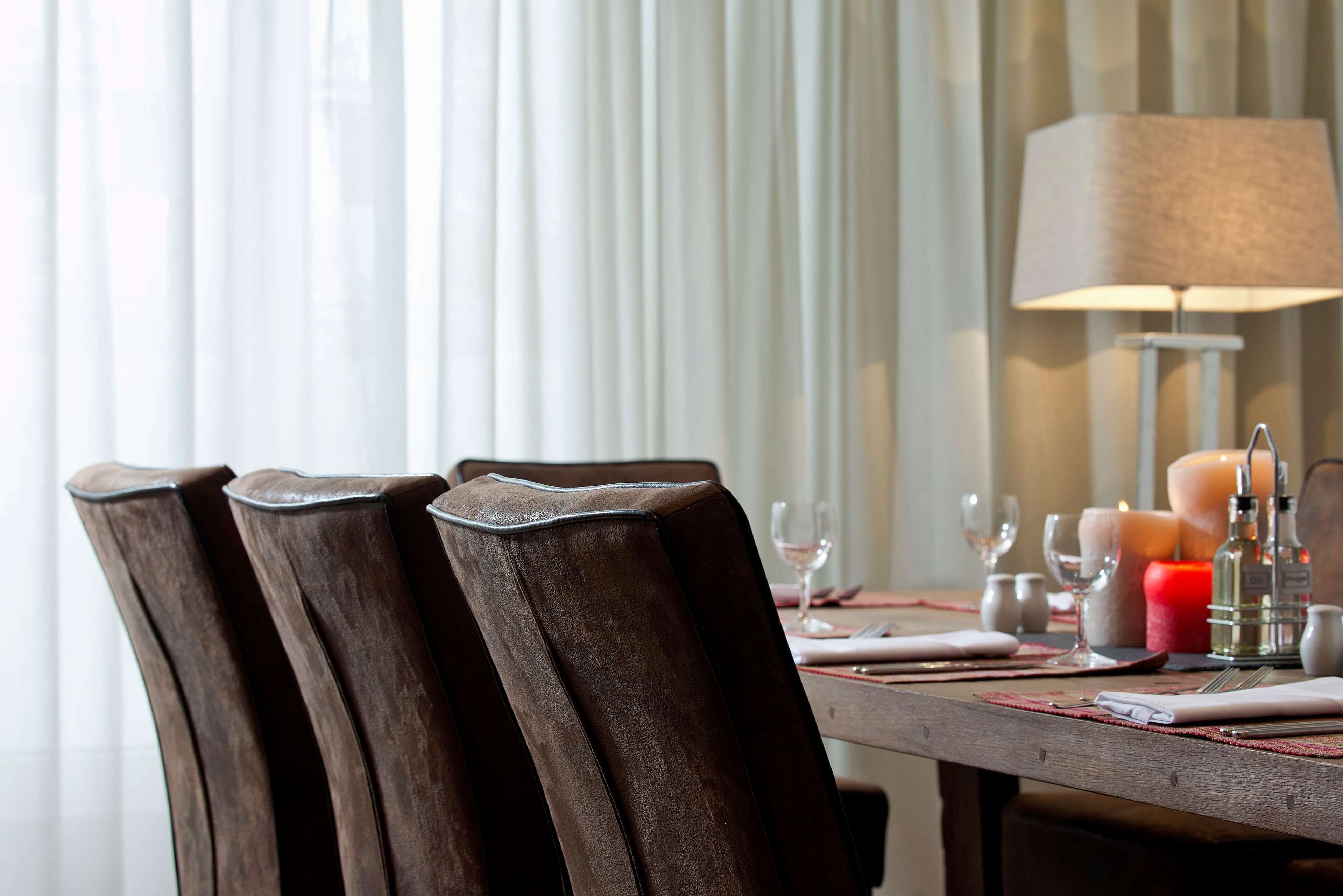 Une table à manger décorée avec des bougies, des verres et une lampe.