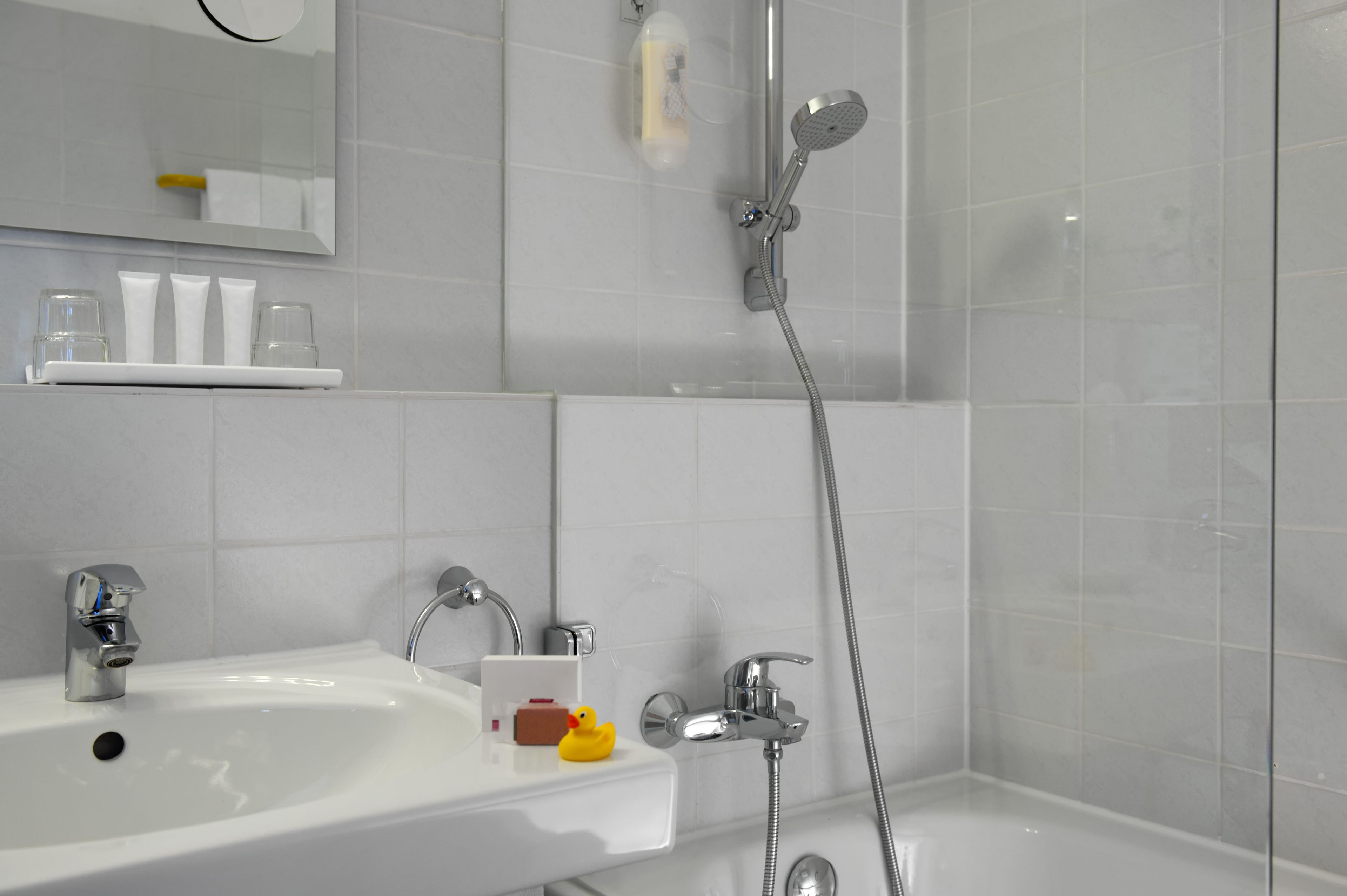 A bathroom with a sink, mirror, and shower.