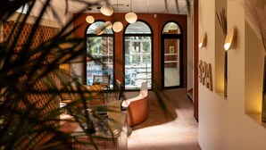 Ein modernes Interieur mit einer gebogenen Rezeption, Pendelleuchten und Blick durch ein großes Rundbogenfenster.