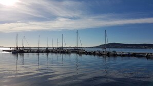 Ein Yachthafen mit vertäuten Booten, ruhigem Wasser und blauem Himmel.