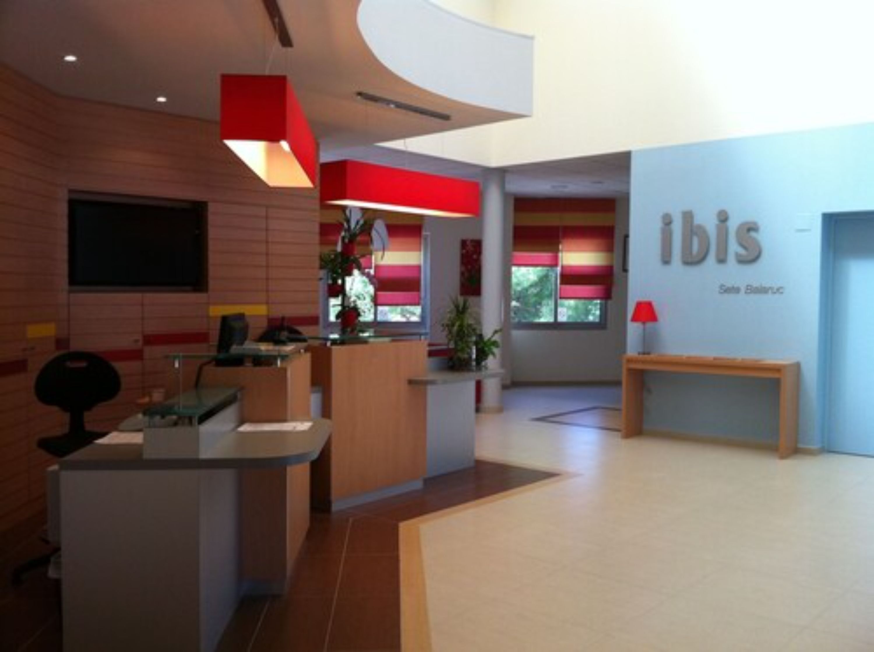 A modern reception area with a counter, seating, and a wall with the name 'ibis'.