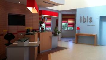 A modern reception area with a counter, seating, and a wall with the name 'ibis'.
